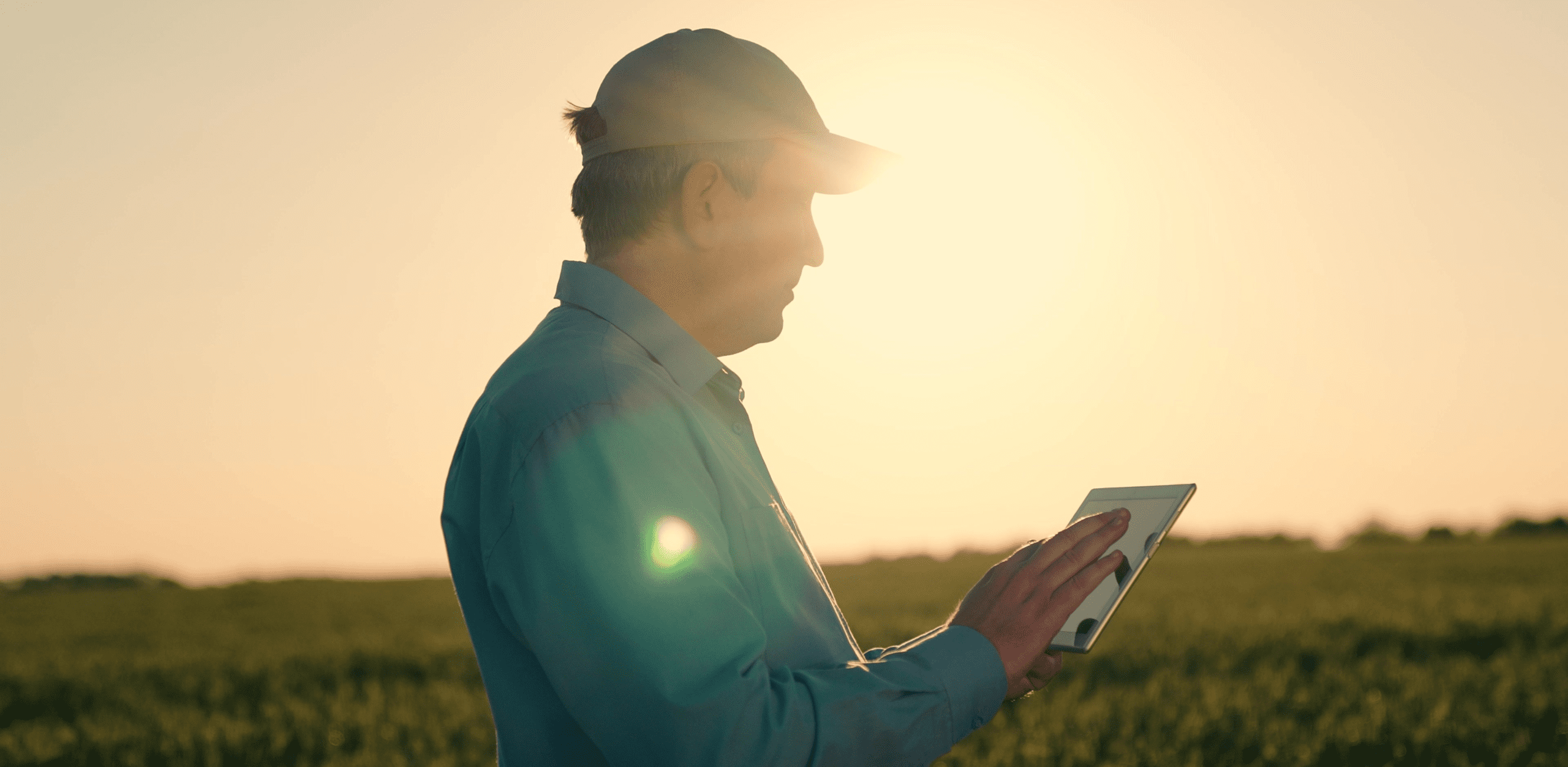 A man in a cap is standing in an open area under the sun.