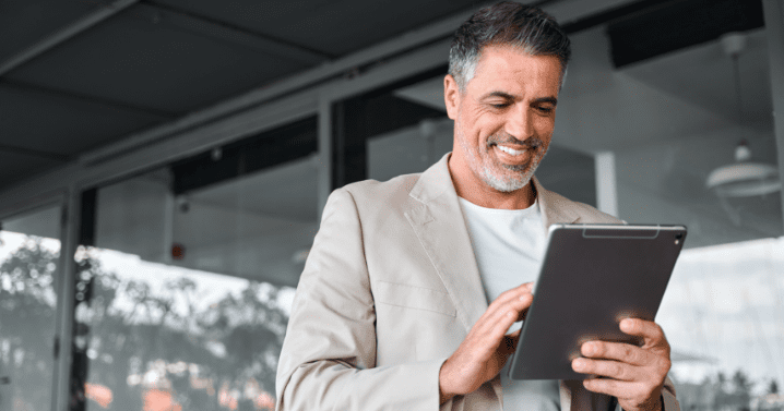 A man is smiling at his tablet.